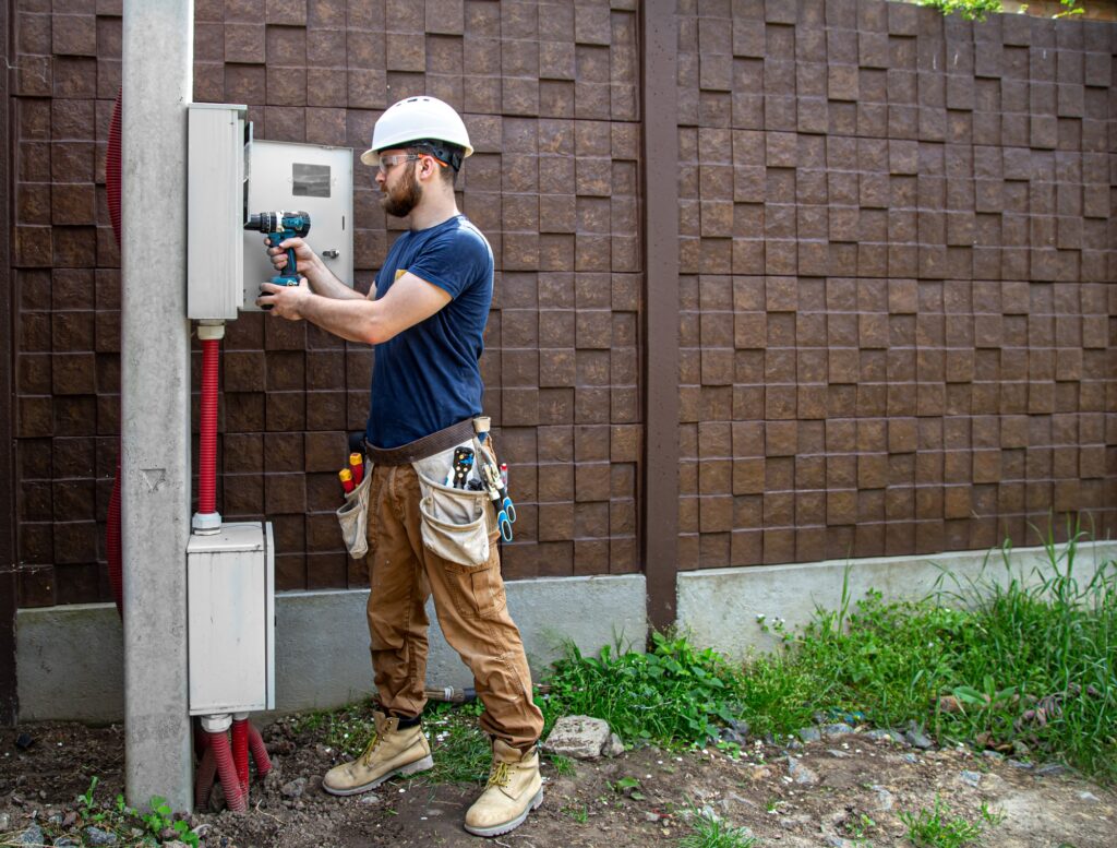 Electrician Builder at work, examines the cable connection in the electrical line.